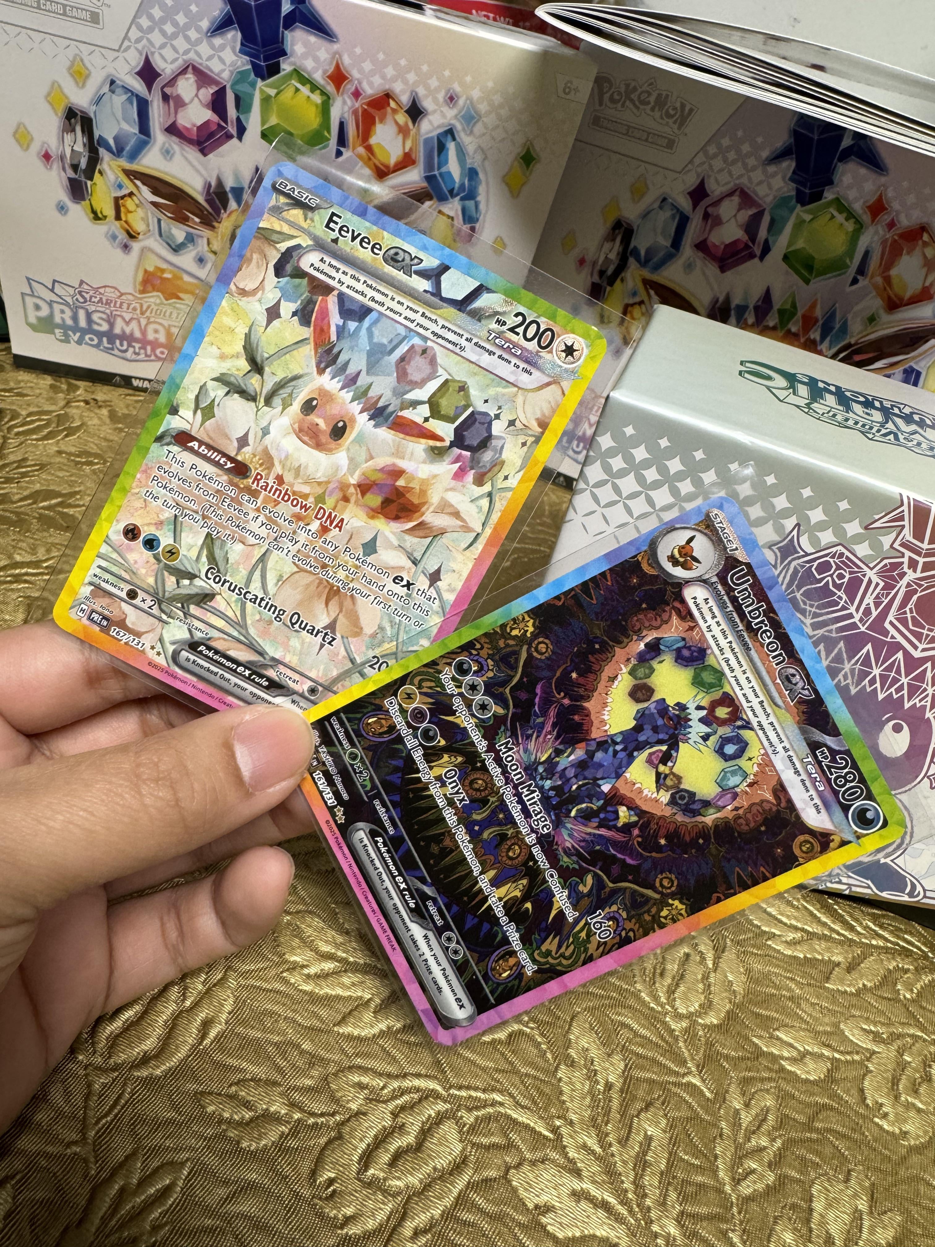 Top Hits
Get the special illustration of Eevee EX.
Get the illustration of Umbreon EX.
Both are from the Prismatic Evolutions Elite Trainer Box. These are sealed Pokémon cards from the Scarlet & Violet set.